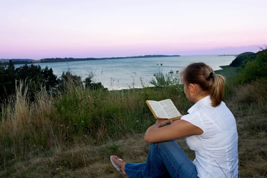 A young Faru sits in the grass and reads a book