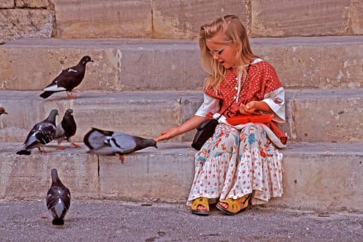 Little girl feeding pigeons