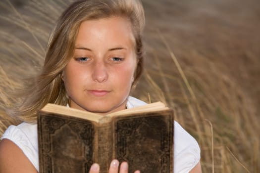 A young woman reads an old book in the background A cornfield