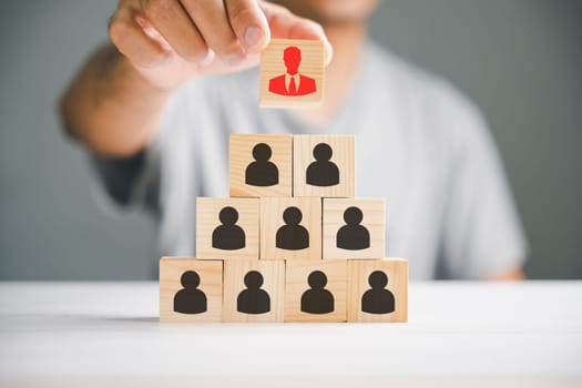 Stock photo illustrating human resources talent management and recruitment. Person icons on wooden cube block symbolize teamwork and organization. Woman leadership concept in a business setting.