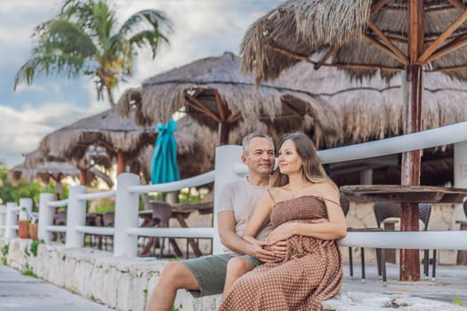 A happy, mature couple over 40, enjoying a leisurely walk in a park, their joy evident as they embrace the journey of pregnancy later in life.