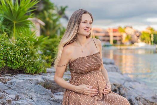 Pregnant woman hugging her tummy standing outdoors surrounded by nature. Pregnancy, expectation, motherhood concept.