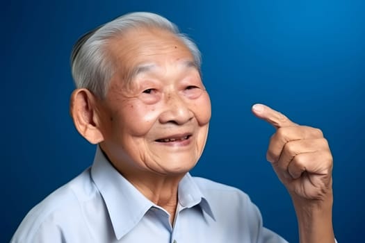 Asian grandfather looking and smiling with rised index finger on blue background. Neural network generated in May 2023. Not based on any actual person, scene or pattern.