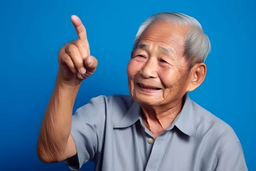 Asian grandfather looking and smiling with rised index finger on blue background. Neural network generated in May 2023. Not based on any actual person, scene or pattern.