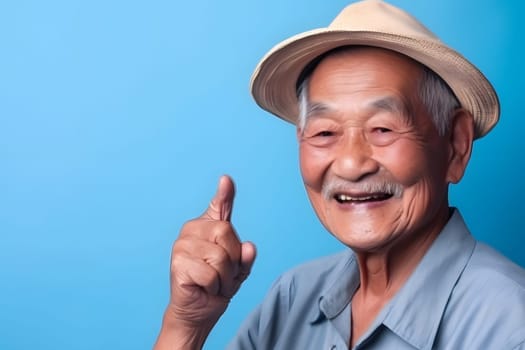 Asian grandfather looking and smiling with rised index finger on blue background. Neural network generated in May 2023. Not based on any actual person, scene or pattern.