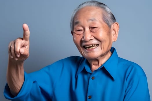 Asian grandfather looking and smiling with rised index finger on blue background. Neural network generated in May 2023. Not based on any actual person, scene or pattern.