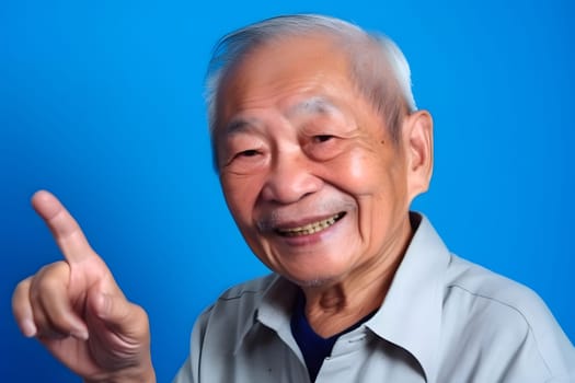 Asian grandfather looking and smiling with rised index finger on blue background. Neural network generated in May 2023. Not based on any actual person, scene or pattern.