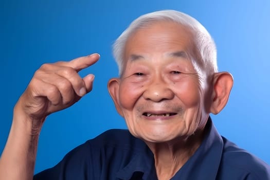 Asian grandfather looking and smiling with rised index finger on blue background. Neural network generated in May 2023. Not based on any actual person, scene or pattern.