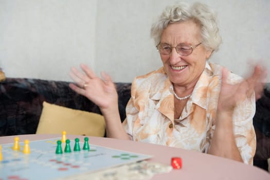 A pensioner rejoices over her success in a board game