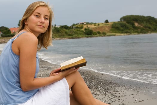 A young woman with a book on the beach