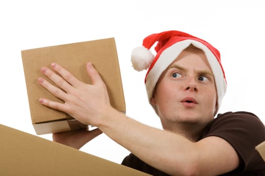 A man with a Santa Claus hat curiously shakes a package