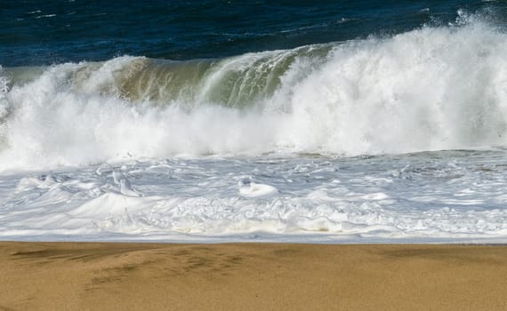 Ocean waves crashing on the sandy beach with the turquoise water rippling and splashing at Lumahai Beach.