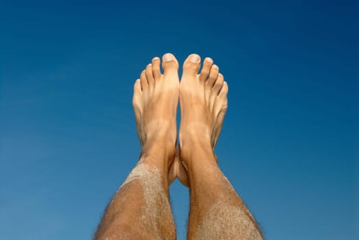 Feet against a blue background. Summertime.