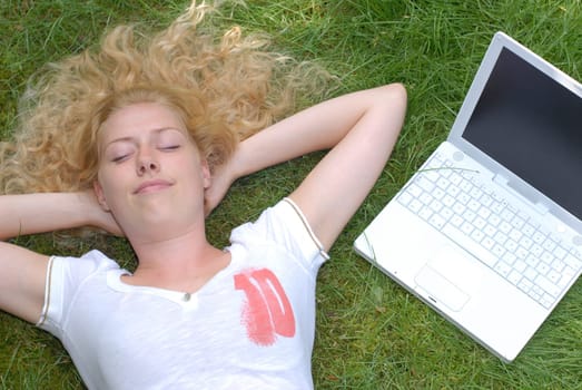 Woman lying with laptop on the lawn