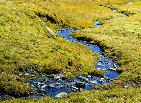 The mountain stream meanders peacefully through the high moor landscape.