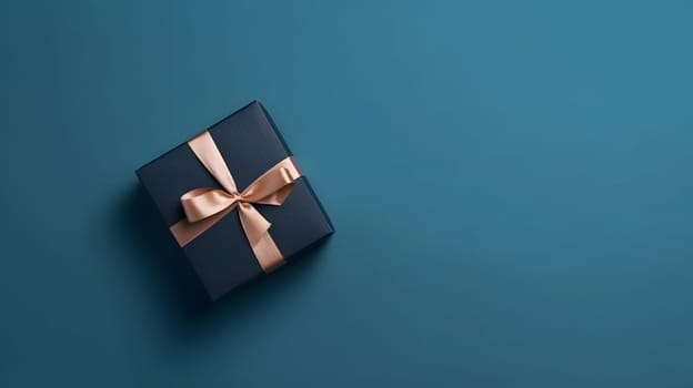 One dark blue gift box in craft wrapping paper and peachy satin ribbon with bow on light blue clean flat surface background. Neural network generated in May 2023. Not based on any actual person, scene or pattern.