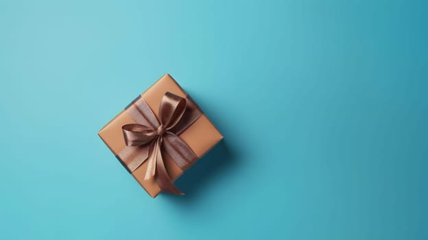 One brown gift box in craft wrapping paper and satin ribbon with bow on light blue clean flat surface background. Neural network generated in May 2023. Not based on any actual person, scene or pattern.