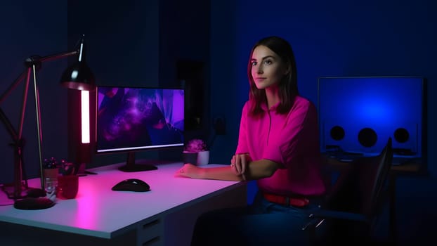designer girl sitting at the table in front of computer in home office at evening. Neural network generated in May 2023. Not based on any actual person, scene or pattern.
