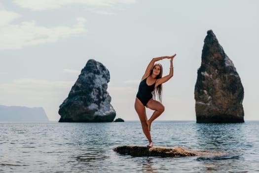 Woman meditating in yoga pose silhouette at the ocean, beach and rock mountains. Motivation and inspirational fit and exercising. Healthy lifestyle outdoors in nature, fitness concept.