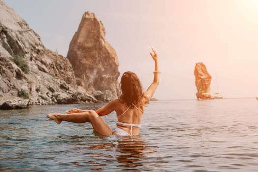 Young woman with black hair, fitness instructor in pink sports leggings and tops, doing pilates on yoga mat with magic pilates ring by the sea on the beach. Female fitness daily yoga concept