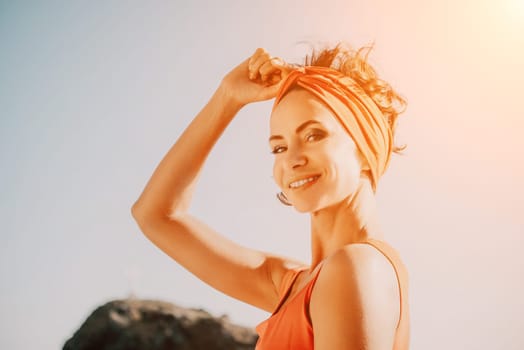 The woman in a red suit practicing yoga on stone at sunrise near the sea. Young beautiful girl in a red bathing suit sits on the seashore in lotus position. Yoga. Healthy lifestyle. Meditation