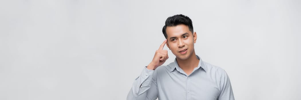 Young man point finger at his head gesture thinking portrait white background