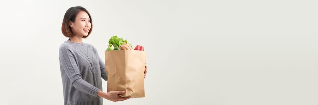 Asian woman with paper bag of fresh vegetable isolated on white background