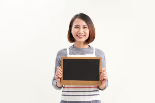 Beautiful woman in barista apron holding empty blackboard on white background isolated