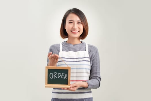 Young woman in apron holding board with order sign standing in white background