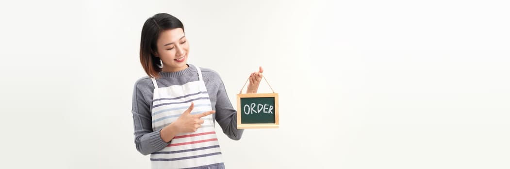 happy female small business owner in apron holding board with order lettering on white background