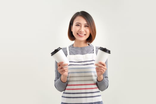 Portrait of kind friendly pleasant girl giving two big lattes isolated on white background