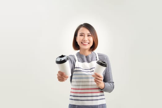 Portrait of kind friendly pleasant girl giving two big lattes isolated on white background
