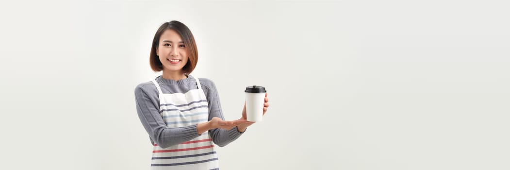 young woman in apron holds two takeaway paper cup isolated over white background