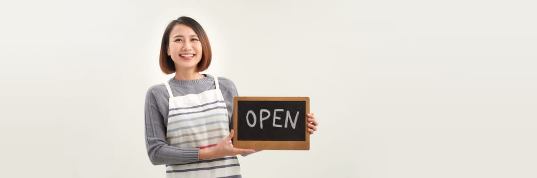 Female business owner in apron holding OPEN sign and smiling isolated on white banner background