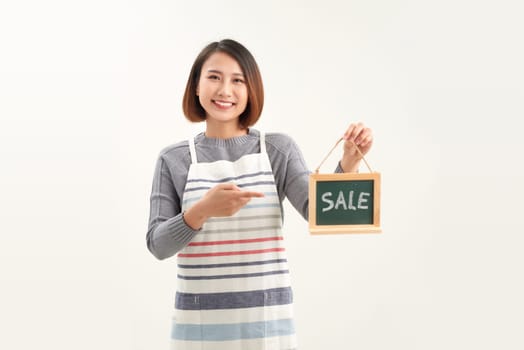 Beautiful asian woman in barista apron holding SALE word blackboard sign on white background