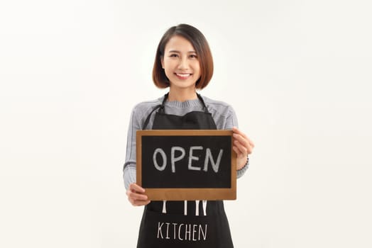 Young asian woman wearing apron holding blackboard with open word smiling on white background