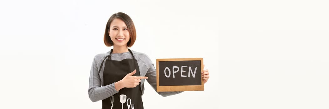 Female business owner in apron holding OPEN sign and smiling isolated on white banner background