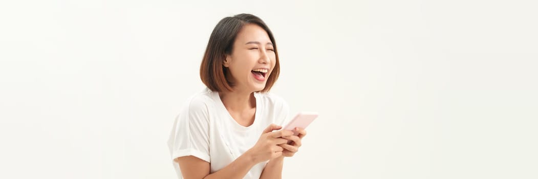 Portrait of excited asian woman using her mobile phone, isolated on white studio background