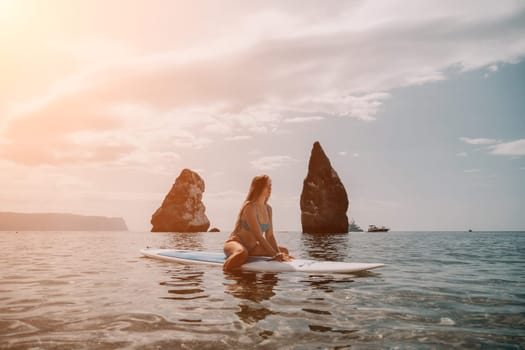 Close up shot of beautiful young caucasian woman with black hair and freckles looking at camera and smiling. Cute woman portrait in a pink bikini posing on a volcanic rock high above the sea