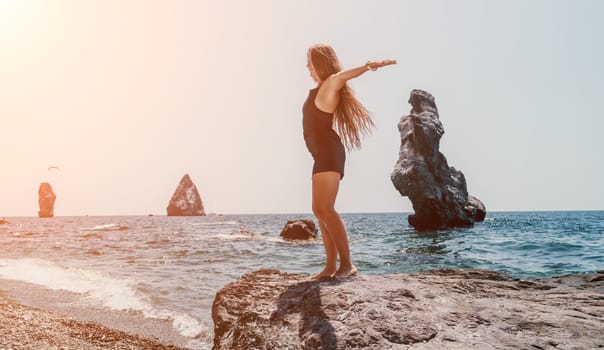 Woman travel sea. Young Happy woman in a long red dress posing on a beach near the sea on background of volcanic rocks, like in Iceland, sharing travel adventure journey