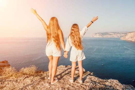 Close up portrait of mom and her teenage daughter hugging and smiling together over sunset sea view. Beautiful woman relaxing with her child.