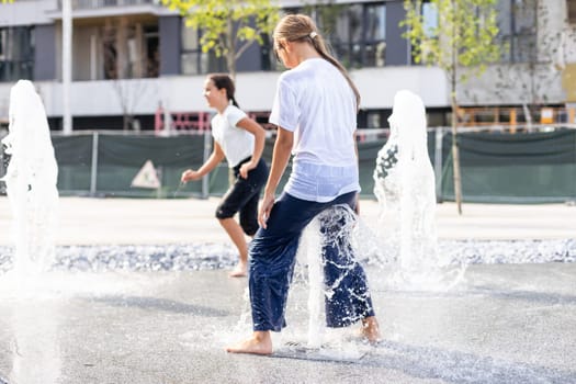 Happy kid playing in a fountain with water. High quality photo