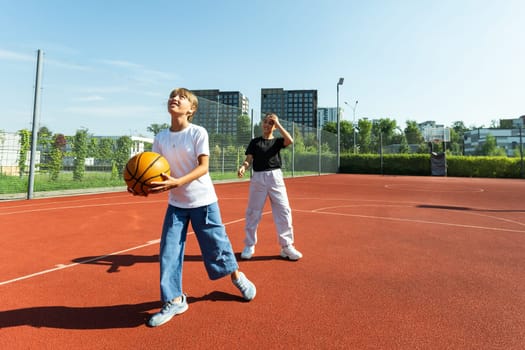 Concept of sports, hobbies and healthy lifestyle. Young people playing basketball on playground outdoors. High quality photo