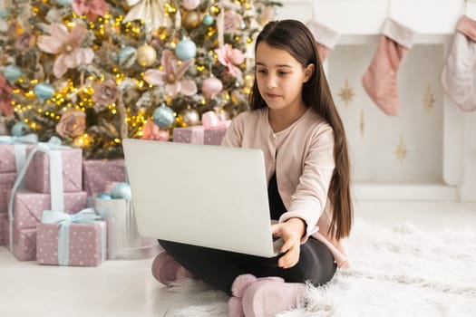 Happy girl using laptop at home during christmas.