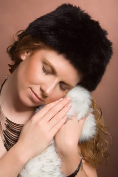 Young,attractive woman snuggles up to faux fur. On the head faux fur hat.