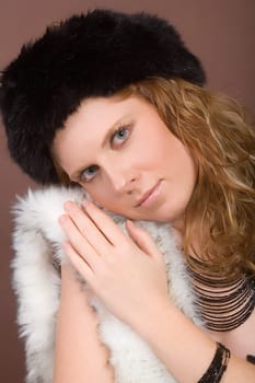 Young,attractive woman snuggles up to faux fur. On the head faux fur hat.