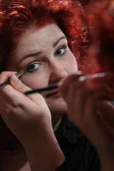 red-haired woman doing makeup