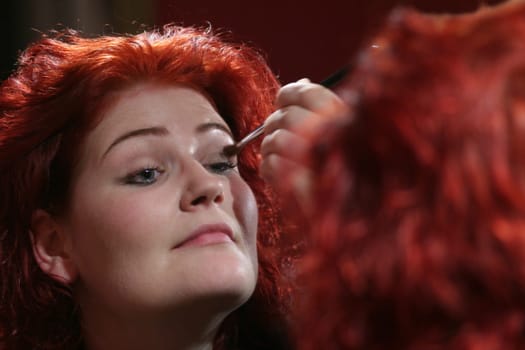 red-haired woman doing makeup