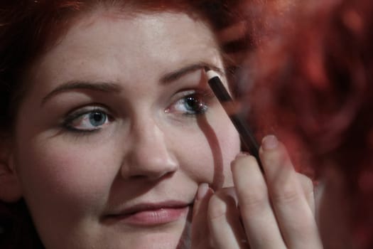 red-haired woman doing makeup