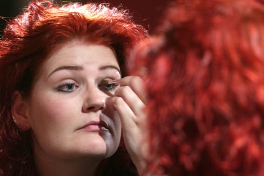 red-haired woman doing makeup